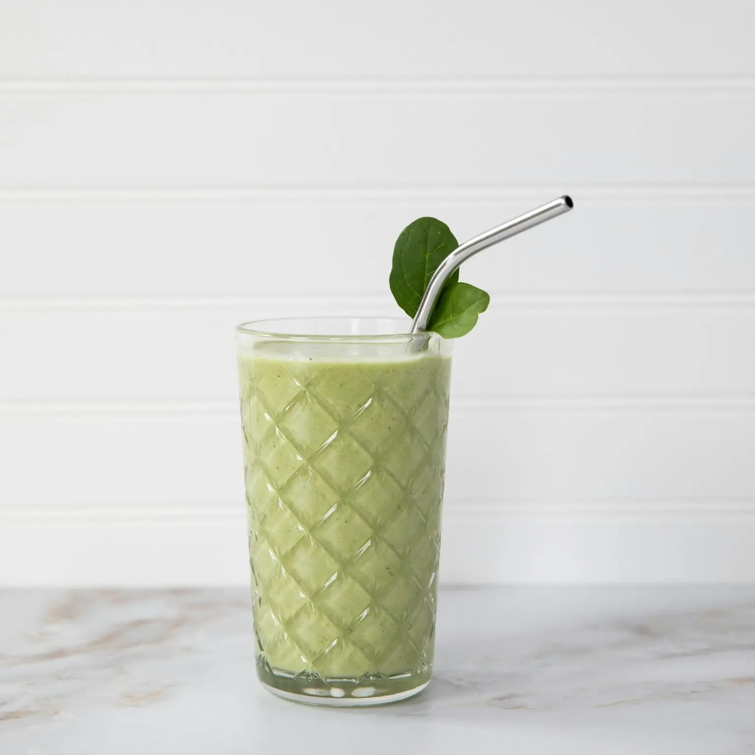 green and white drink with straw in clear drinking glass